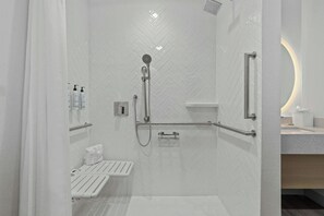 A modern shower area with a white tiled wall, a handheld showerhead, a handheld shower attachment, and a grab bar. - TownePlace Suites by Marriott Nashville Brentwood (Brentwood)