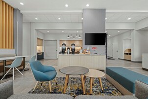 Un lobby moderno con zonas de estar, una estación de café y un televisor de pantalla plana.