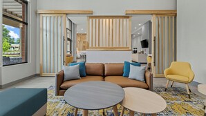 Um interior moderno com um sofá modular, duas mesas redondas e uma cadeira amarela.
