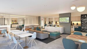 En modern hotellobby med sittgrupper, en tv-skärm och en receptionsdisk.