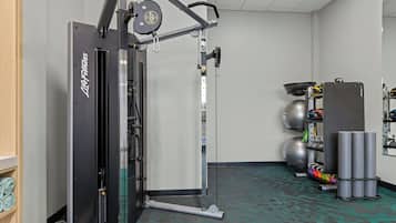 A gym with a cable machine, exercise balls, and a weight rack.