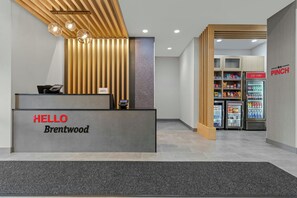 A reception desk with a 'HELLO Brentwood' sign, a cash register, and a wall-mounted phone.