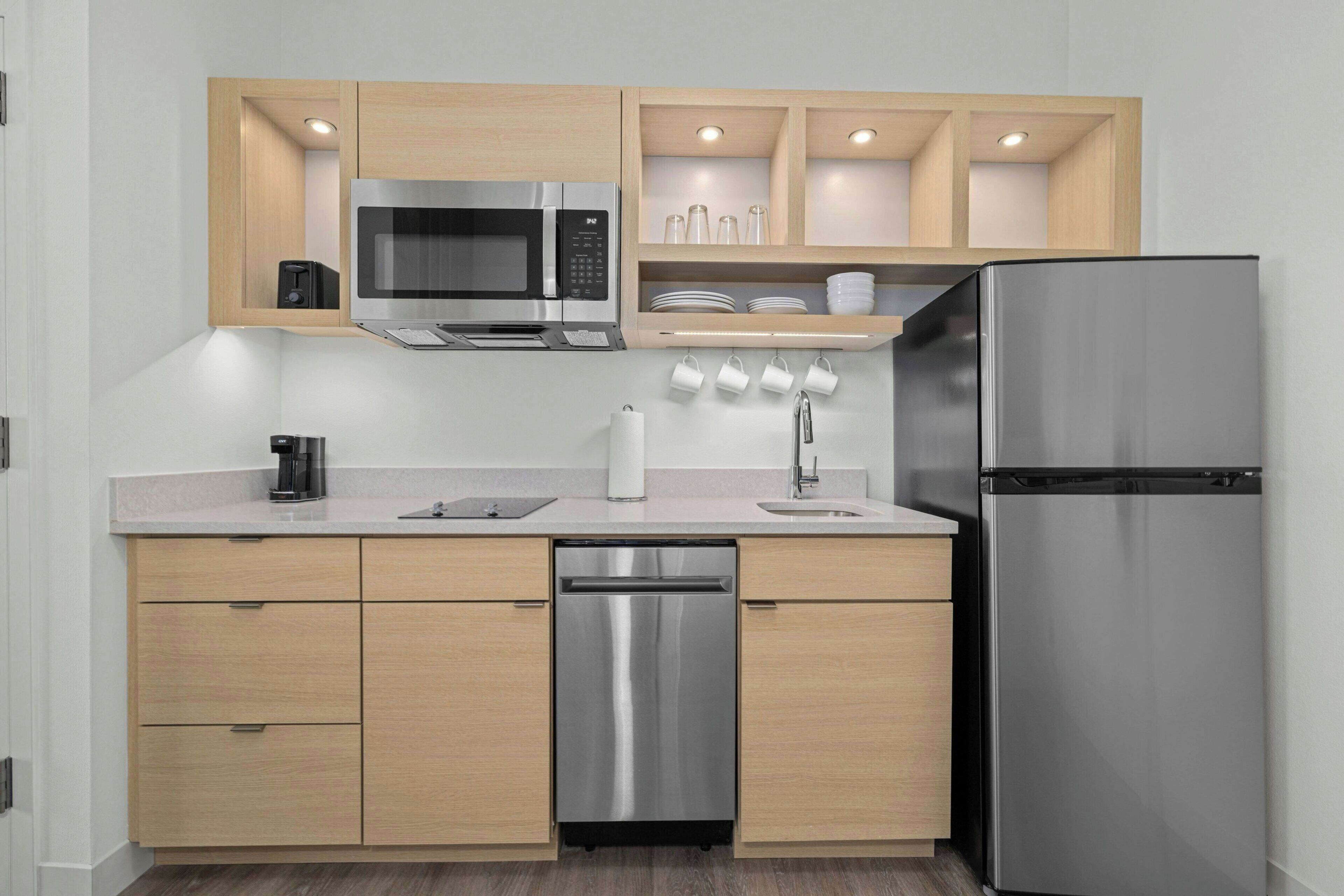 A modern kitchen with stainless steel appliances, wooden cabinets, and a built-in dishwasher.