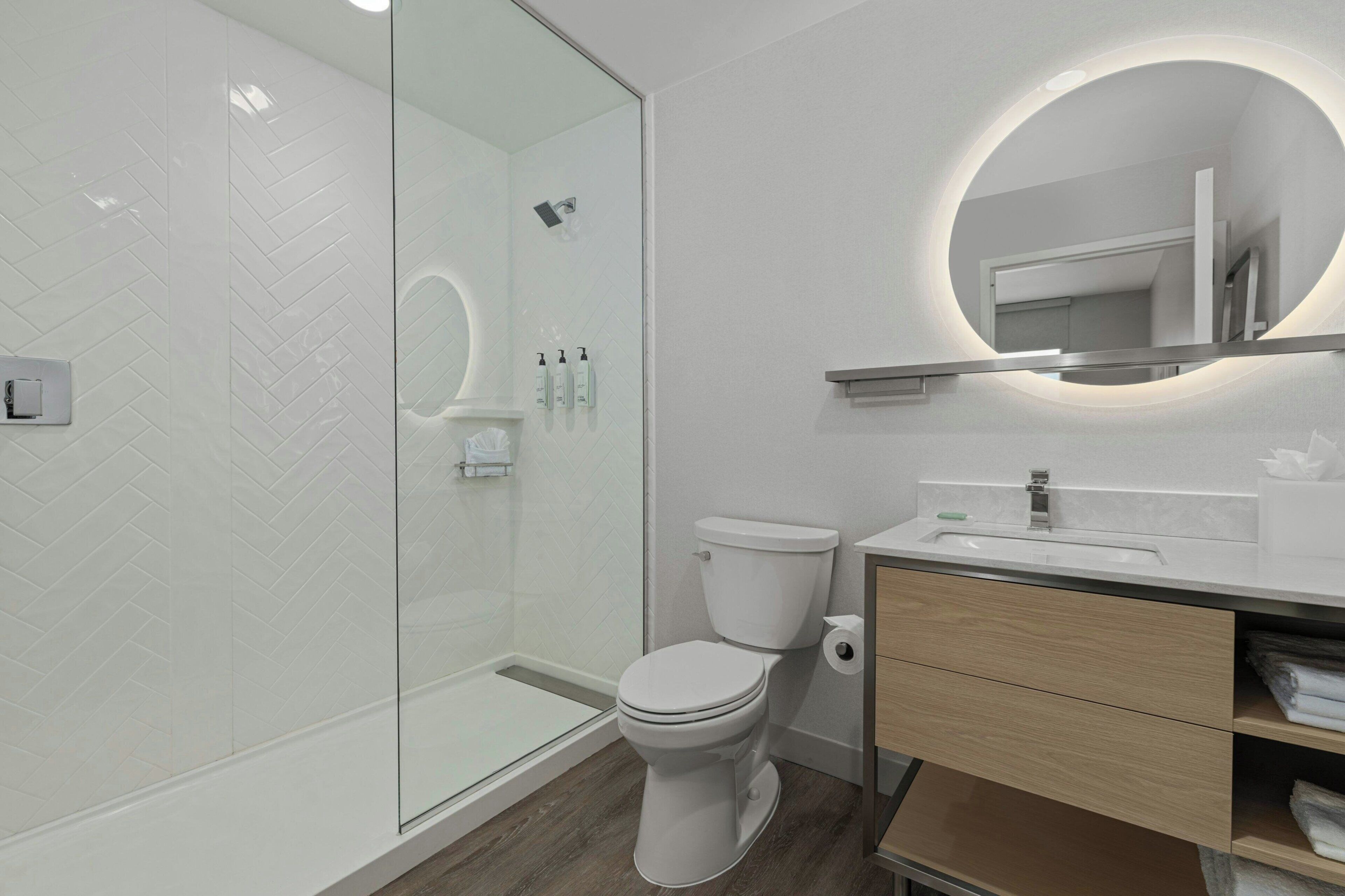 A modern bathroom with a glass shower enclosure, a toilet, and a vanity with a mirror.