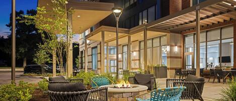 An outdoor seating area with wicker chairs, a fire pit, and a covered patio.