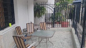 A patio with a table and chairs, a window with a metal grill, and a potted plant. - Studio 3 Paisible 5 Minutes From El Rodadero Beach (Santa Marta)