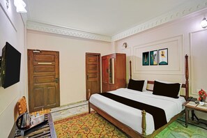 A hotel room with a large bed, wooden wardrobe, a flat-screen TV, and a bedside table with a vase of flowers. - Palette Hotel and Resorts Jodhpur (Jodhpur)