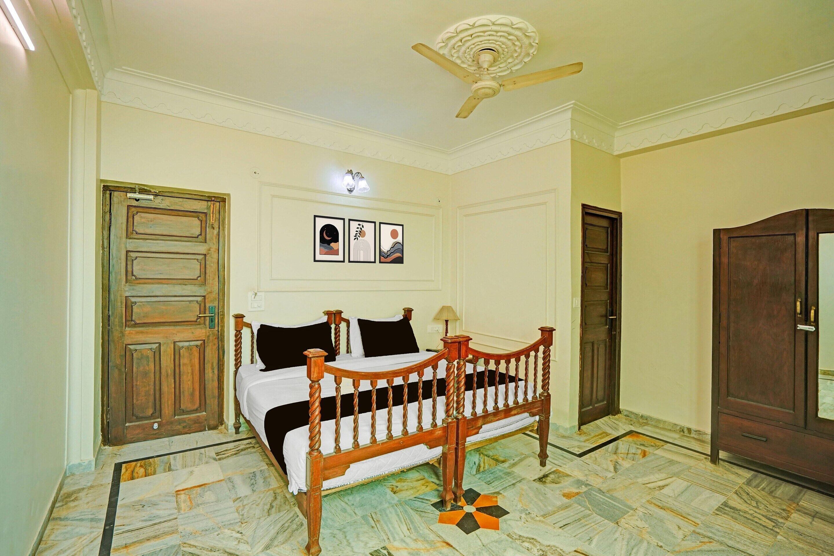 A bedroom with a wooden bed, a ceiling fan, a door, and a wall-mounted light fixture.