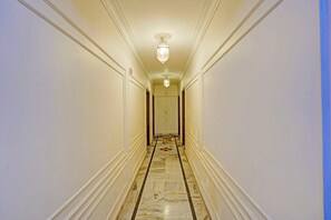 A hotel hallway with marble flooring, white walls, and a ceiling light fixture. - Palette Hotel and Resorts Jodhpur (Jodhpur)