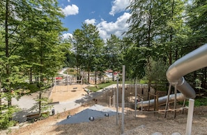 A playground with slides, swings, and climbing structures surrounded by trees. - Studio Robert mit Pool und Sauna (Freyung)