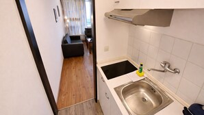 A narrow hallway leading to a kitchen with a sink, a small table, and a sofa in the background. - Studio Robert mit Pool und Sauna (Freyung)