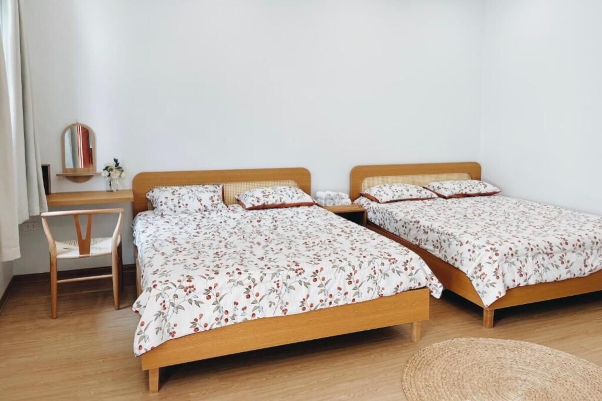 A room with two wooden beds, a small desk, a chair, and a mirror.