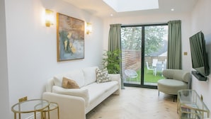 Un salon moderne avec un canapé, un fauteuil, une table basse en verre et un tableau accroché au mur.