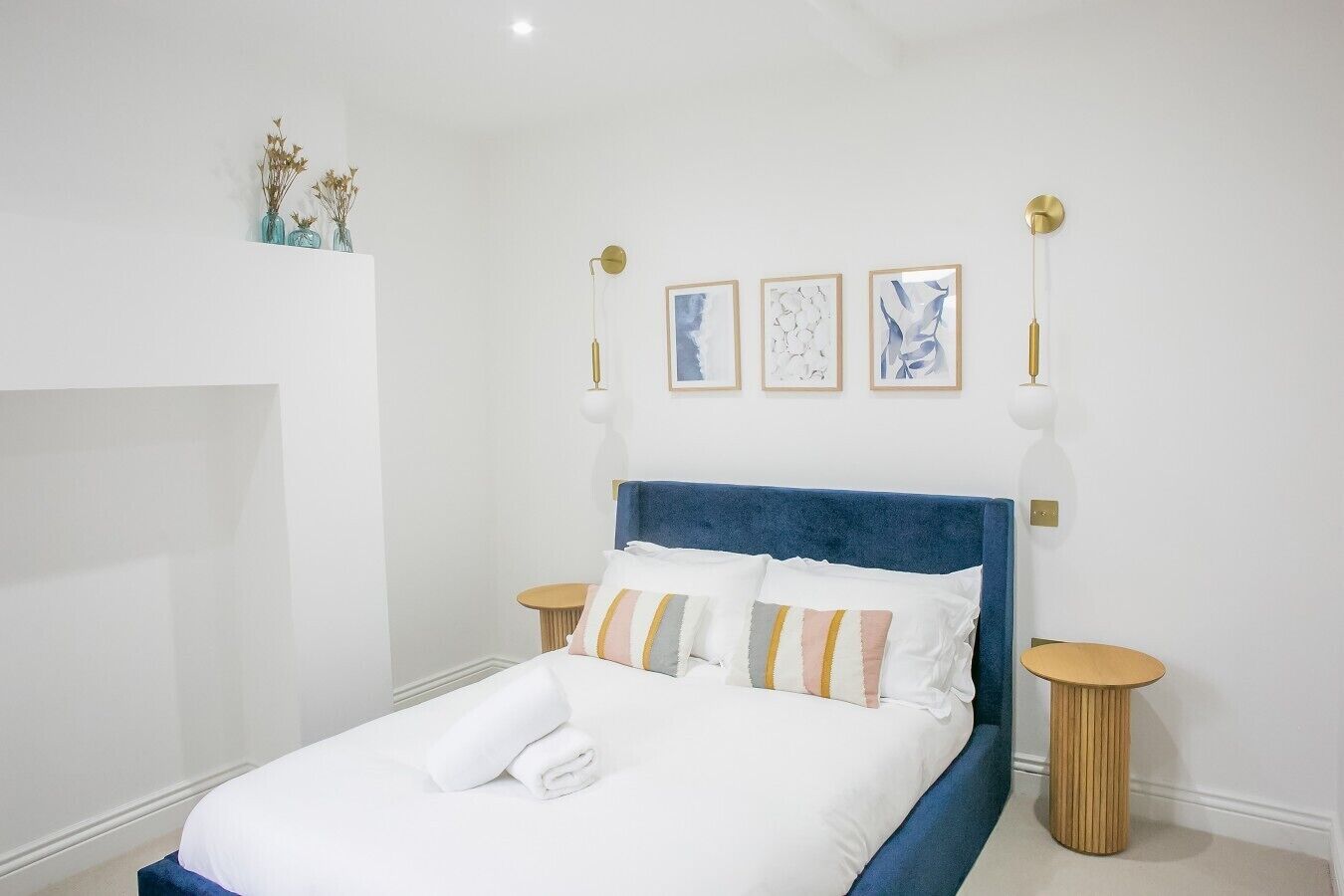 A bedroom with a bed, bedside tables, and wall-mounted lamps.