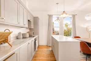 Eine moderne Küche mit weißen Schränken, einer Holzauskładung und einem Essbereich mit Tisch und Stühlen.