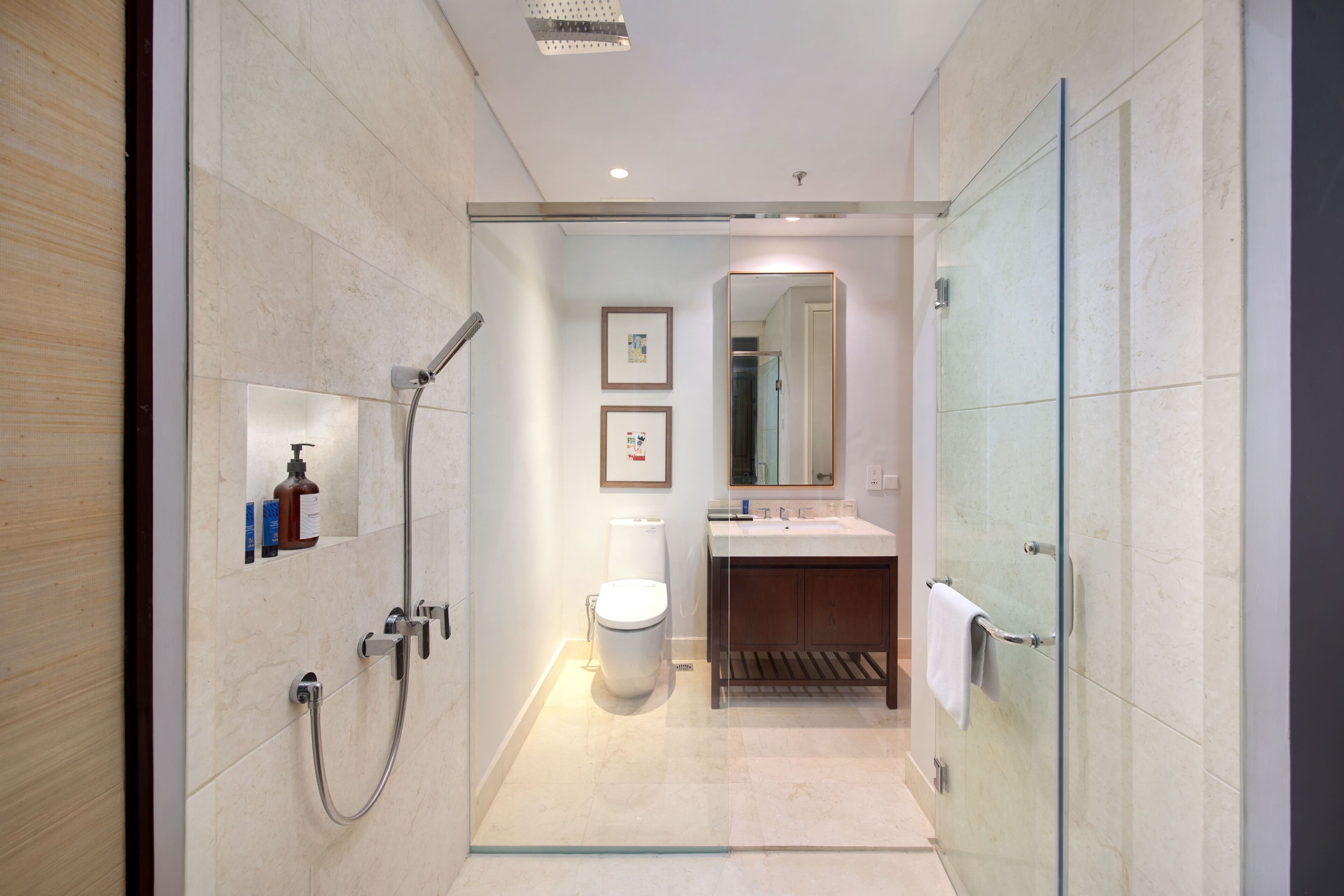 A modern bathroom with a glass shower enclosure, a toilet, a sink, and a mirror.