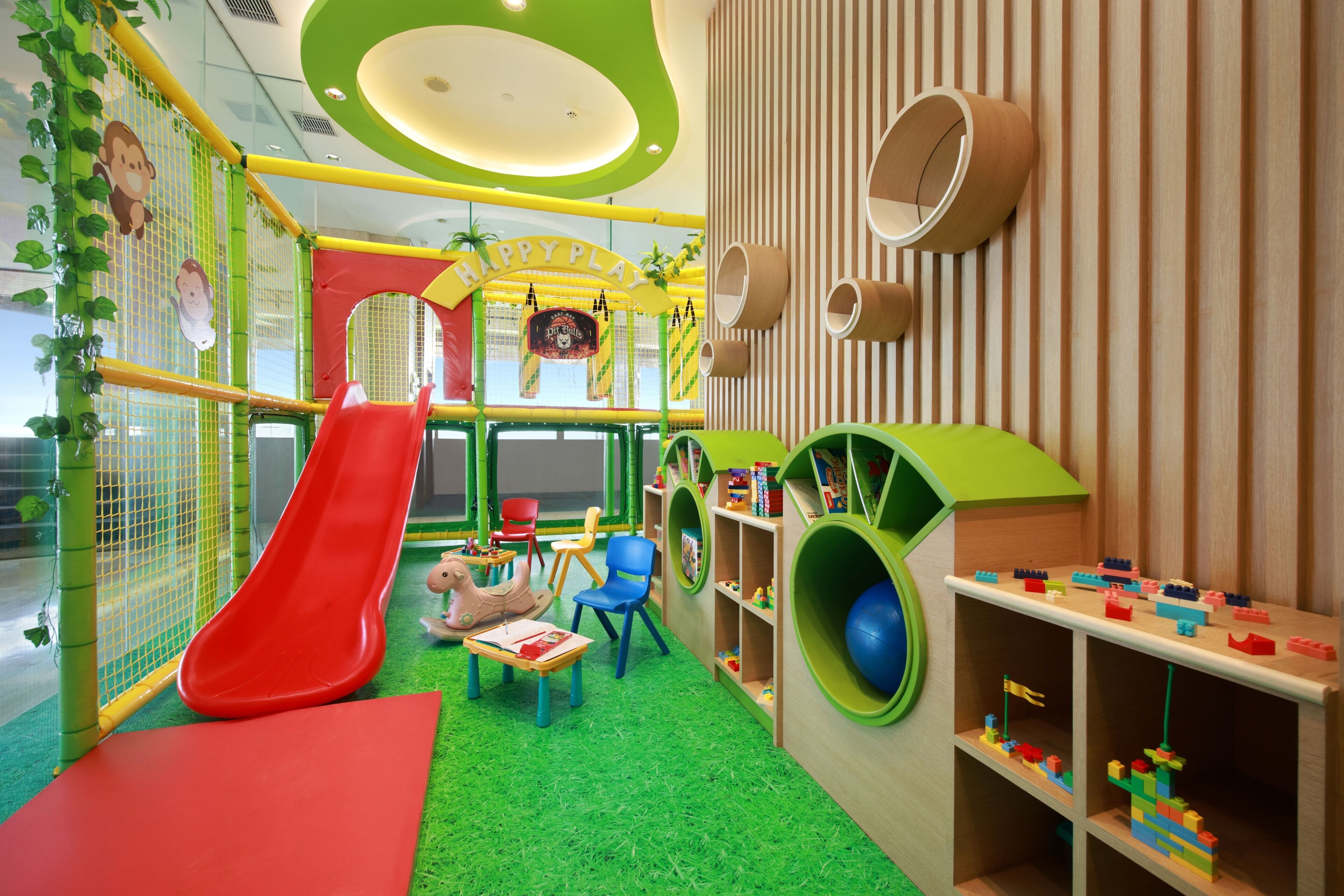 Zona infantil con tobogán, red de escalada y mesas de juegos.