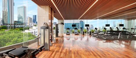 A gym with exercise equipment, large windows, and a city view.