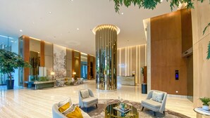 A spacious lobby with a reception desk, seating area, and a large decorative column. - Vasa Suite Surabaya (Surabaya)