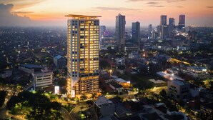 A high-rise hotel with multiple floors, surrounded by a cityscape at dusk. - Vasa Suite Surabaya (Surabaya)