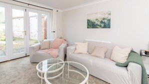 Ein Wohnzimmer mit einer Couch, Sesseln, einem Glastisch und einem Bild an der Wand.