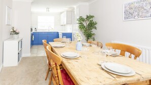 Ein Essbereich mit einem Holztisch, gedeckt für vier Personen, blauen Schränken im Hintergrund und einer gerahmten Karte an der Wand.