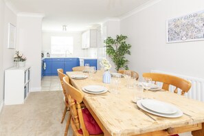 A dining area with a wooden table set for four, blue cabinets in the background, and a framed map on the wall.