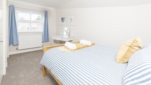 Ein Schlafzimmer mit einem Bett, einem Nachttisch, einem Fenster mit Vorhängen und einer Heizung.