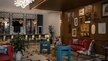 A modern bar area with a bar counter, seating, and a large chandelier.
