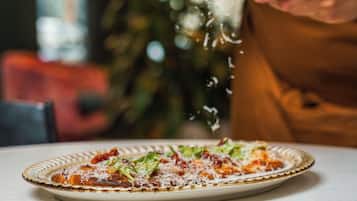 Una persona rallando queso sobre una pizza en un plato.