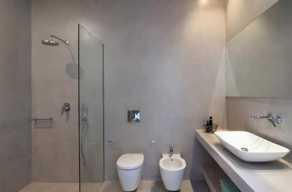 Een moderne badkamer met een douchecabine van glas, een toilet, een bidet en een groot wastafel.