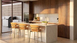 Een moderne keuken met een marmeren eiland, houten keukenkastjes en een groot raam.