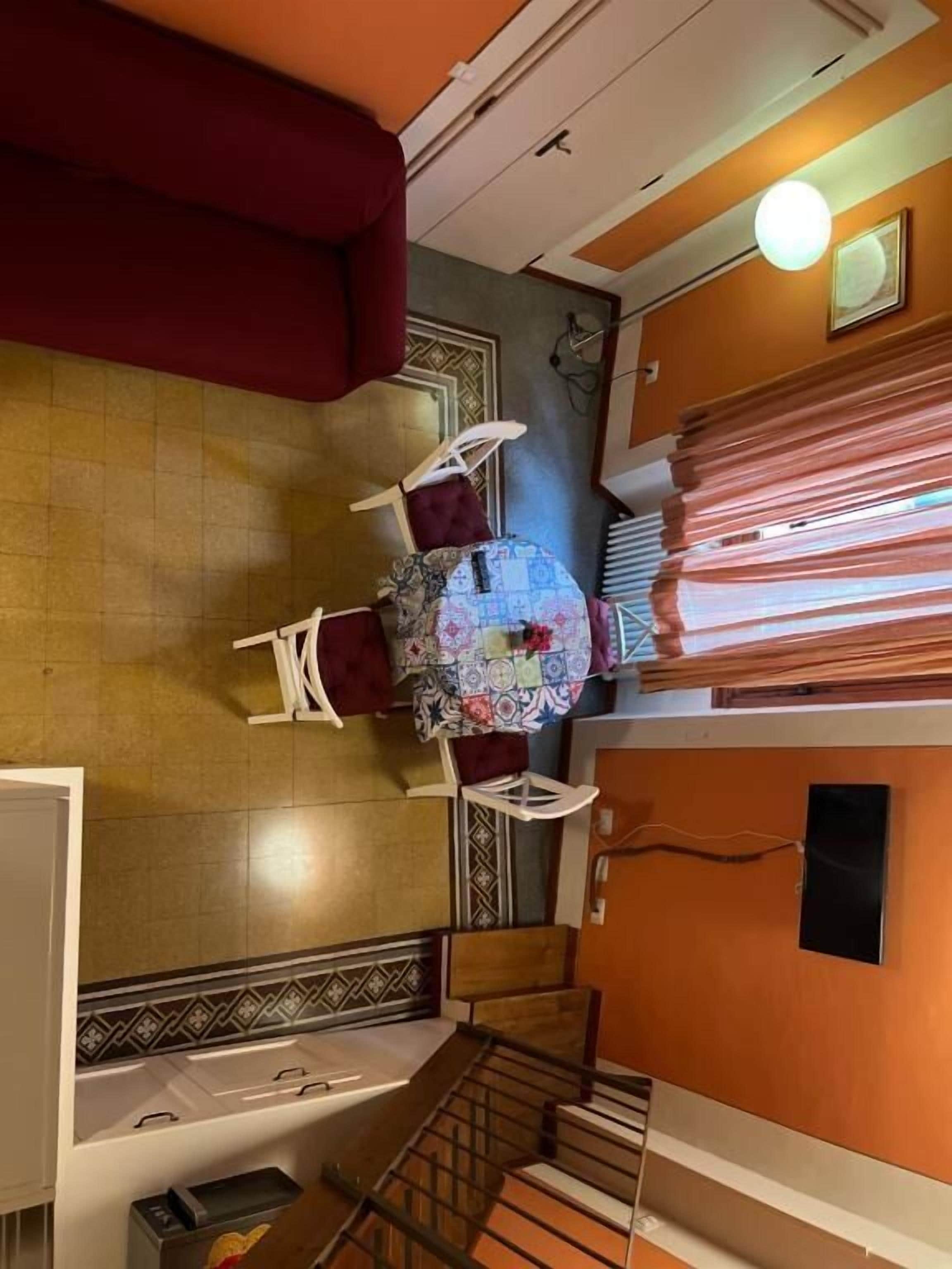 Um quarto com uma mesa redonda, cadeiras, um sofá, uma escada e um chão estampado.