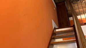 A staircase with wooden steps and a handrail, leading to a room with an orange wall and a decorative ceiling. - Tosca (Florence)