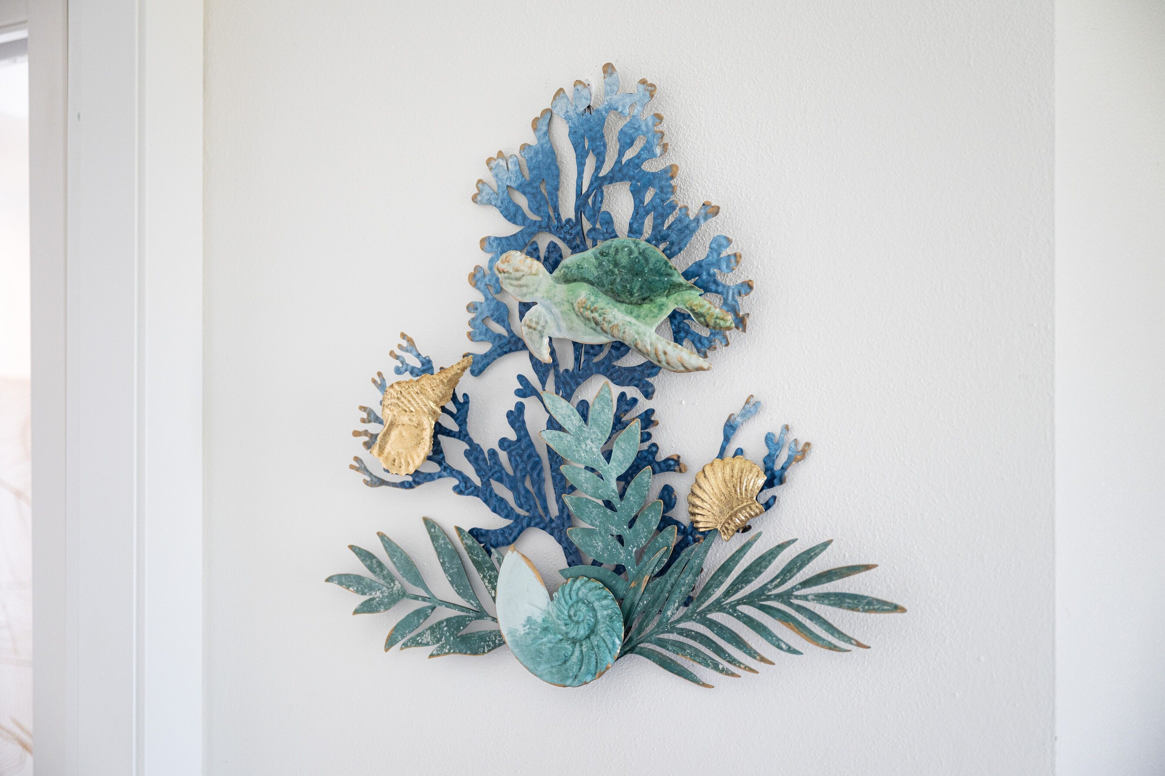 A wall decoration with a turtle, seaweed, and shells.