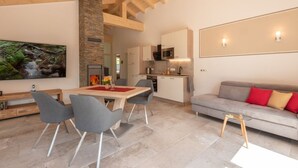 Ein modernes Interieur mit Essbereich, Küche und Wohnbereich, das freiliegende Holzbalken, Steindekorationen und moderne Möbel präsentiert.