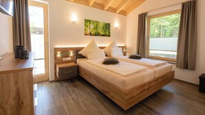 Ein Schlafzimmer mit einem hölzernen Bett, Nachttischen, einem Fenstersims, einem Gemälde und einem Vorhangfenster.