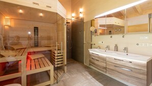 Ein modernes Badezimmer mit einer gläsernen Sauna, einem großen Spiegel und einem hölzernen Waschtisch.