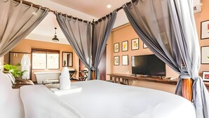 A hotel room with a large bed, curtains, a TV, a desk, and a chair. - Naptel Changmoi (Chiang Mai)