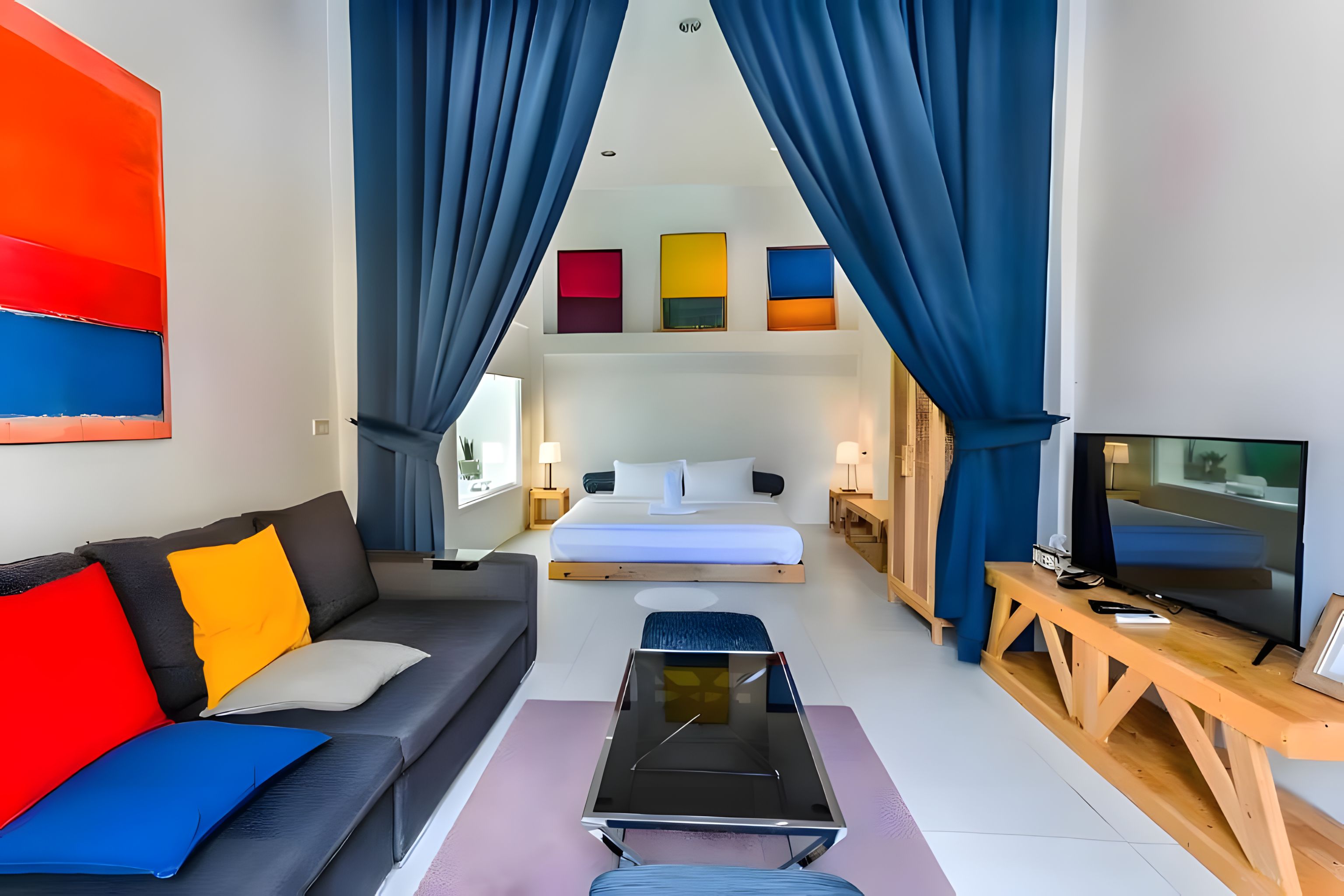 Una habitación de hotel moderna con sofá, cama, televisión y una mesa de centro.