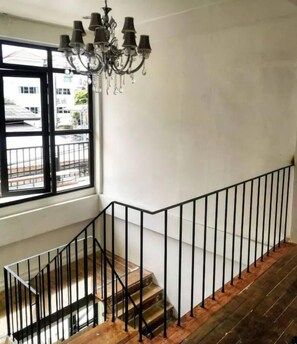 A staircase with a black railing, wooden steps, and a chandelier. - Naptel Changmoi (Chiang Mai)