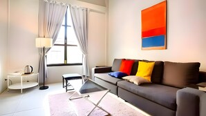 A modern living room with a sofa, a coffee table, a lamp, and a large window with curtains. - Naptel Changmoi (Chiang Mai)