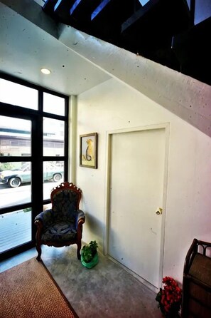 A room with a large window, a door, a chair, and a small plant. - Naptel Changmoi (Chiang Mai)