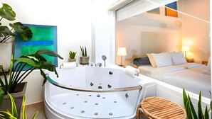 A modern bathroom with a freestanding bathtub, a small seating area, and a large window offering a view of a bedroom. - Naptel Changmoi (Chiang Mai)
