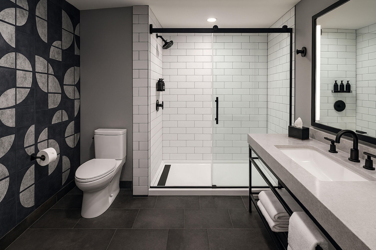 A modern bathroom with a toilet, a shower, and a sink.