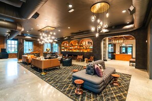 A spacious lobby with a central seating area, a fireplace, and a bar. - The Lawrence Hotel Lawrenceville, Tapestry Collection Hilton (Lawrenceville)