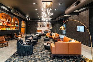 A modern lounge area with seating, a fireplace, and a bookshelf. - The Lawrence Hotel Lawrenceville, Tapestry Collection Hilton (Lawrenceville)