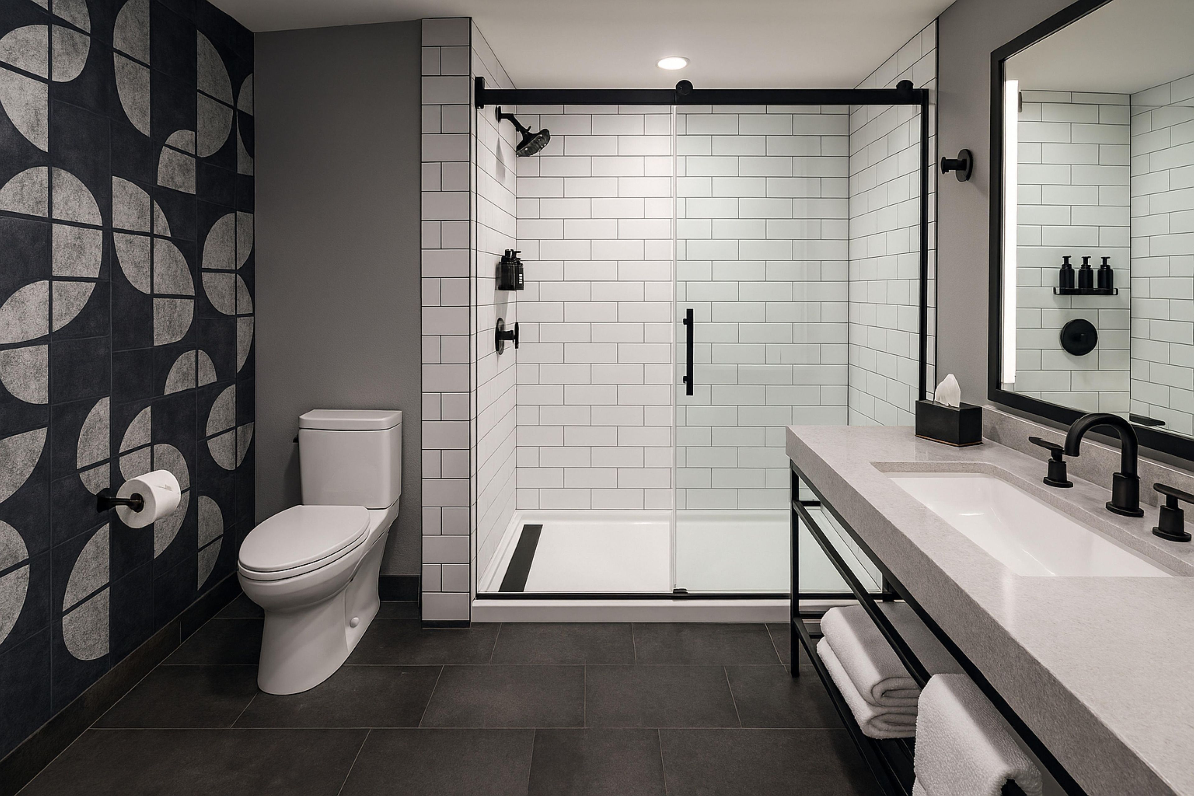 A modern bathroom with a toilet, shower, and sink.