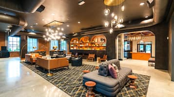 A spacious lobby with a central seating area, a fireplace, and a bar.
