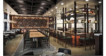 Un restaurante con una larga mesa de madera, sillas y una pared de leña apilada.